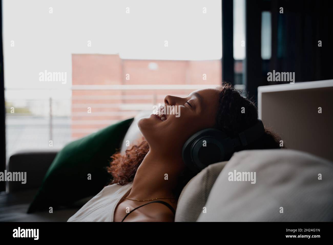 Femme multi-ethnique se reposant sur le lit tout en écoutant de la musique souriant heureux Banque D'Images