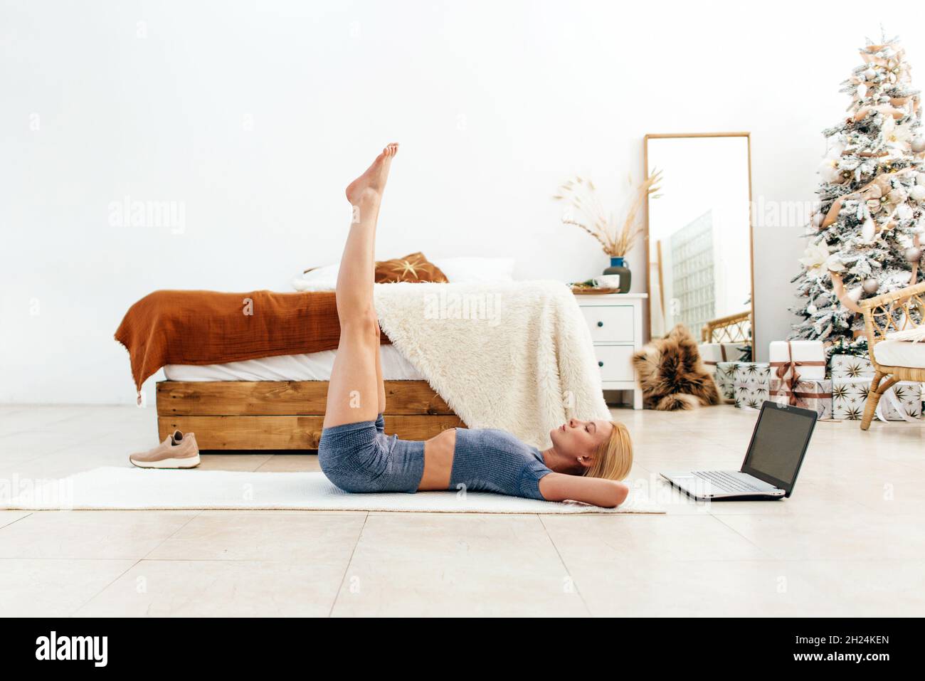 Une femme entraîne les muscles abdominaux en levant les jambes, allongé sur le sol. Banque D'Images