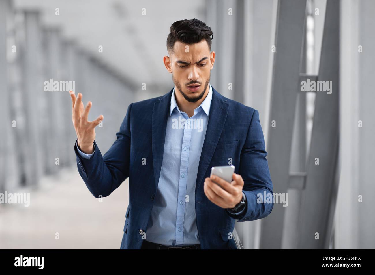 Portrait d'un homme d'affaires arabe inquiet lisant un message sur un smartphone à l'aéroport Banque D'Images