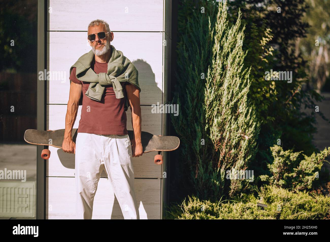 Homme sportif et mature avec le skateboard posé pour la caméra Banque D'Images