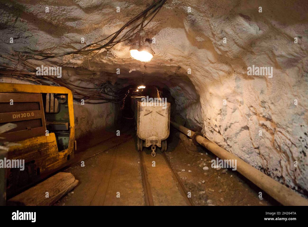 Panier huche avec matière première debout à l'exploitation minière souterraine. La technologie de production et de concept. Tunnel avec l'électricité et des chemins de câbles de la mine Banque D'Images