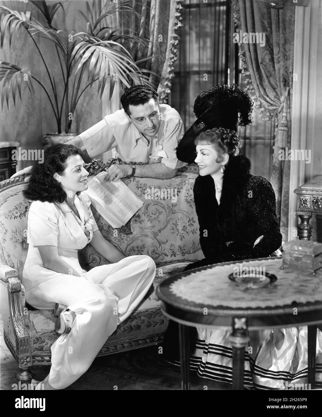 Scène de visiteur l'actrice LENORE ULRIC le directeur de visite GEORGE CUKOR et CLAUDETTE COLBERT sur scène Candid pendant le tournage de ZAZA 1938 réalisateur GEORGE CUKOR costume design Edith Head Paramount Pictures Banque D'Images