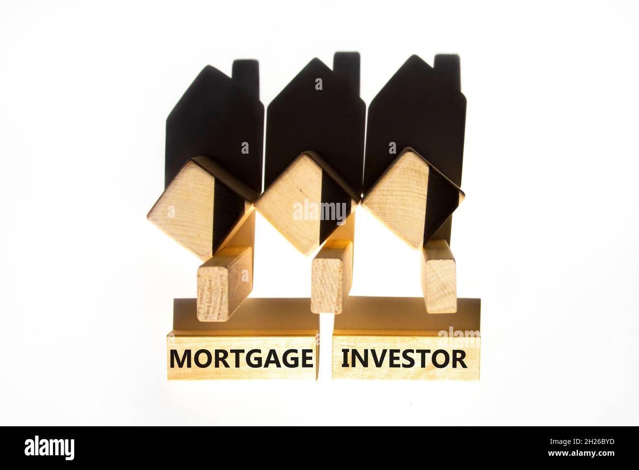 Symbole investisseur hypothécaire.Mots-concepts 'Mortgage investisseur' sur des blocs de bois près de maisons miniatures en bois de l'ombre.Magnifique fond blanc.Unité commerciale Banque D'Images