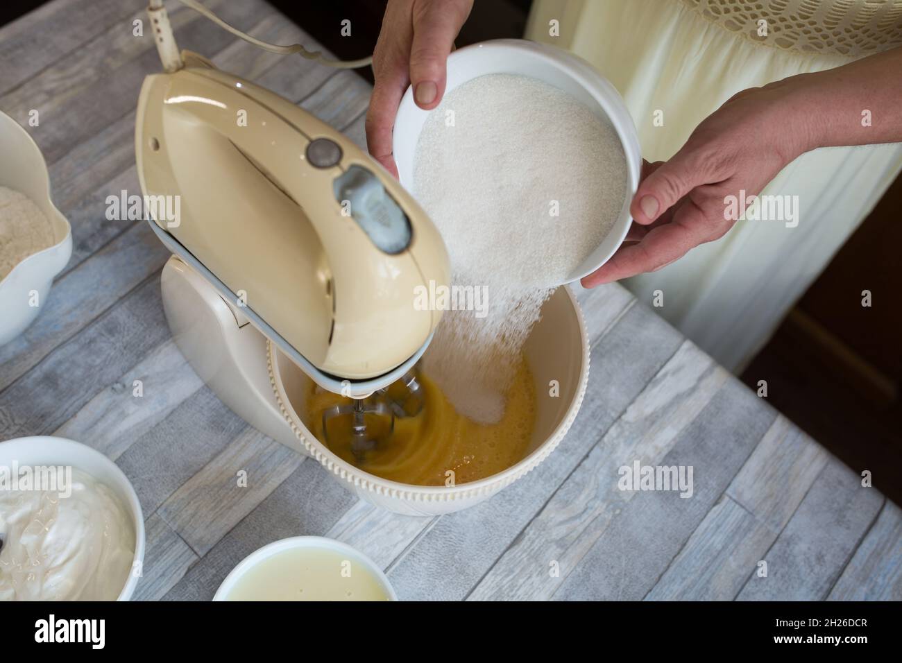 Le processus de fabrication d'un gâteau au chocolat à la crème aigre.Préparation de la pâte.La femme ajoute du sucre dans le bol du batteur.Recette étape par étape pour gâteau au chocolat. Banque D'Images