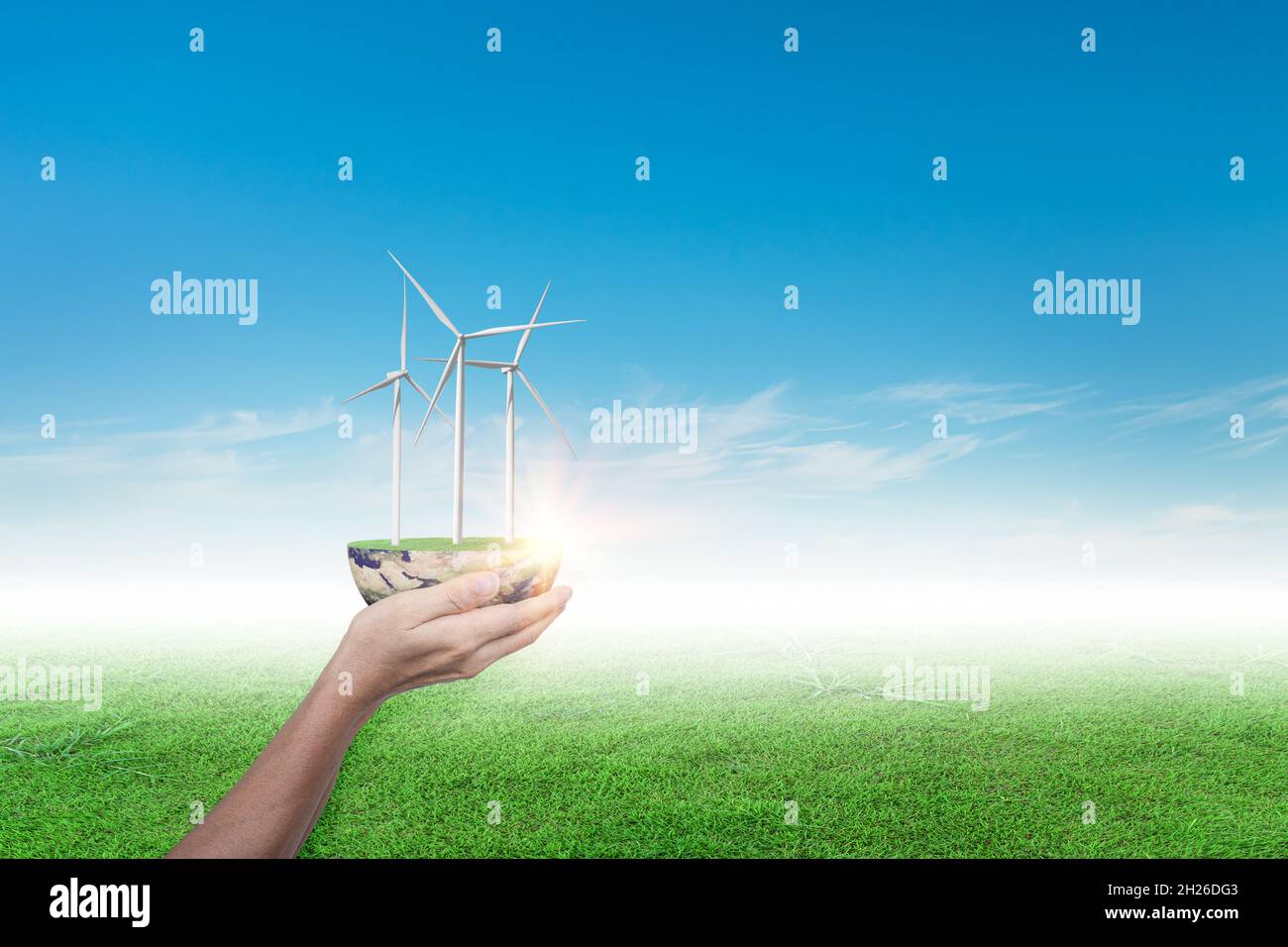 Mains tenant l'éolienne sur le terrain d'herbe contre fond bleu ciel. Concept d'écologie Banque D'Images
