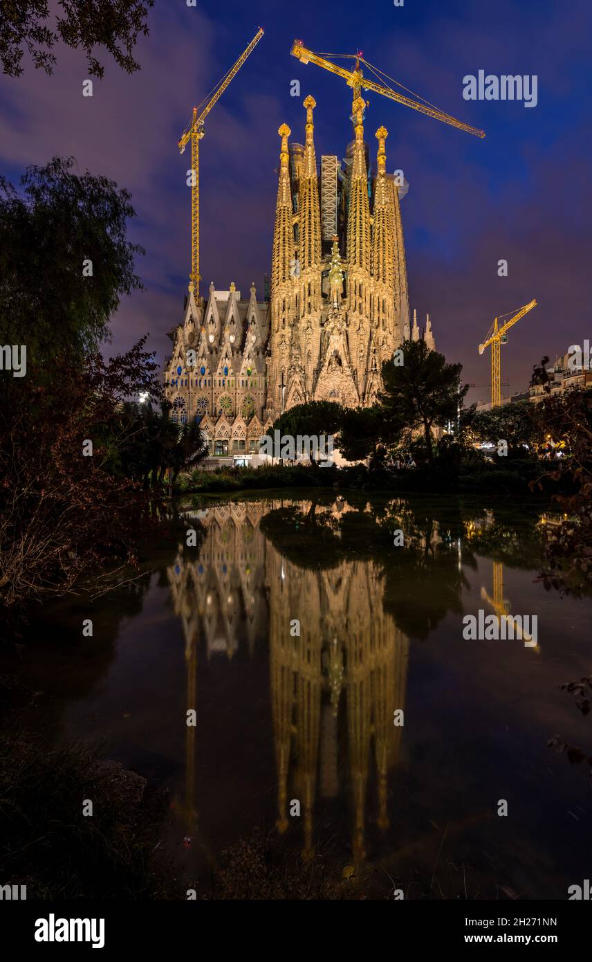 Sagrada Familia - Une vue nocturne verticale de la façade est de la Nativité de la Basílica de la Sagrada Família se reflète dans un petit étang, Barcelone, Espagne. Banque D'Images