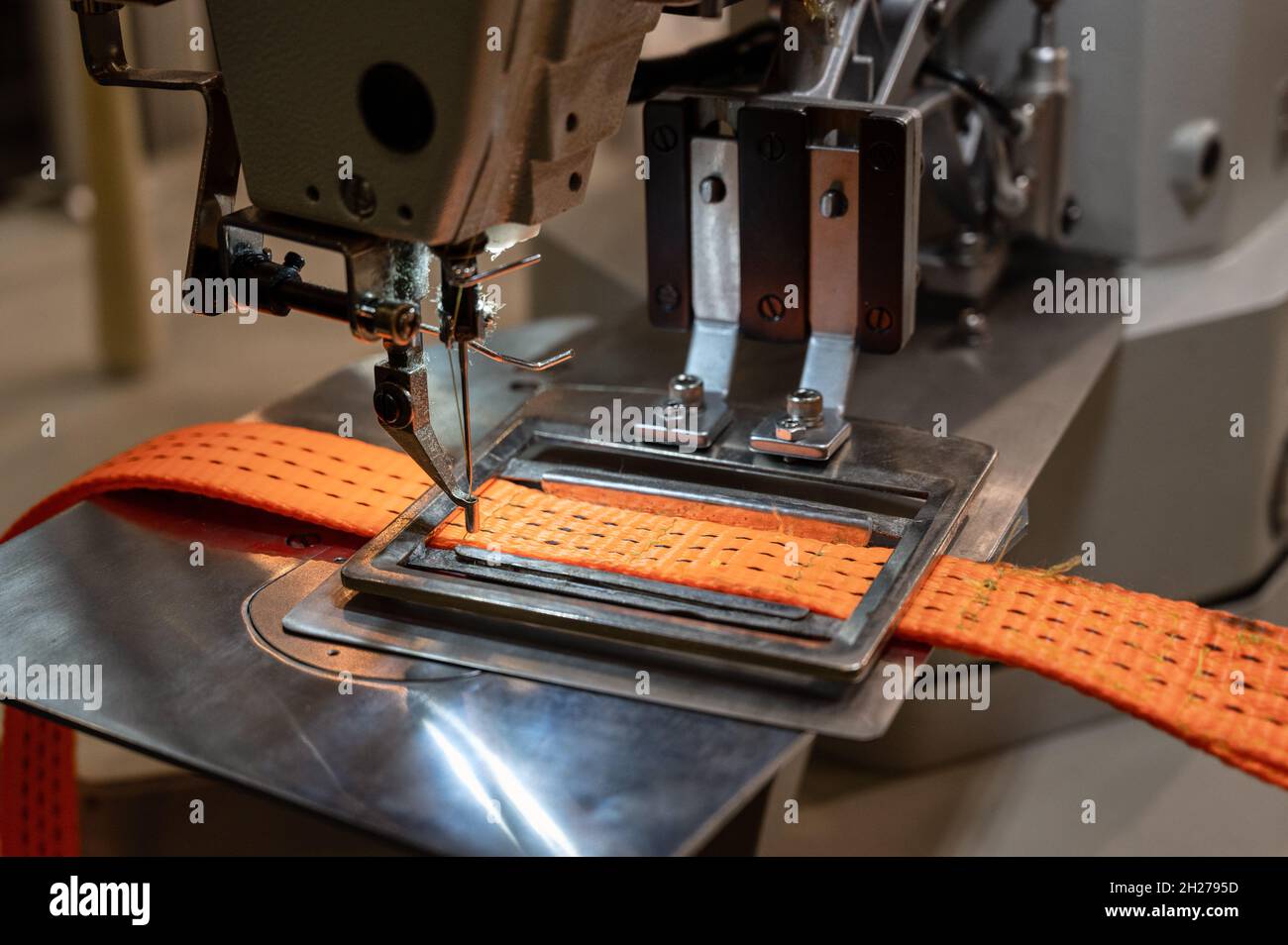 La machine à coudre fonctionne avec une sangle de remorquage orange en  atelier Photo Stock - Alamy