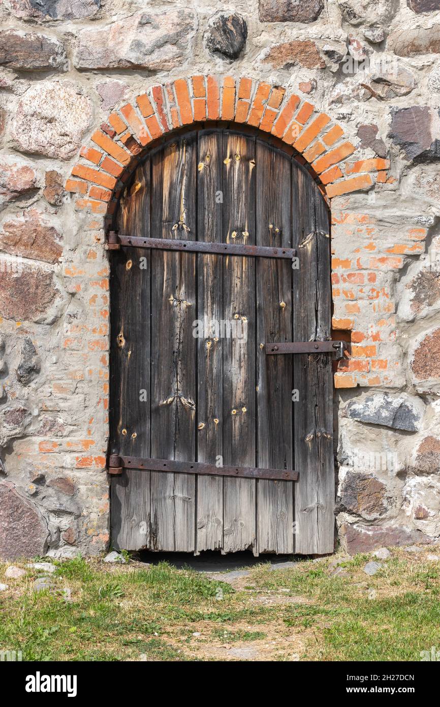 Ancienne porte en bois voûtée dans un mur en pierre, texture photo d'arrière-plan verticale Banque D'Images
