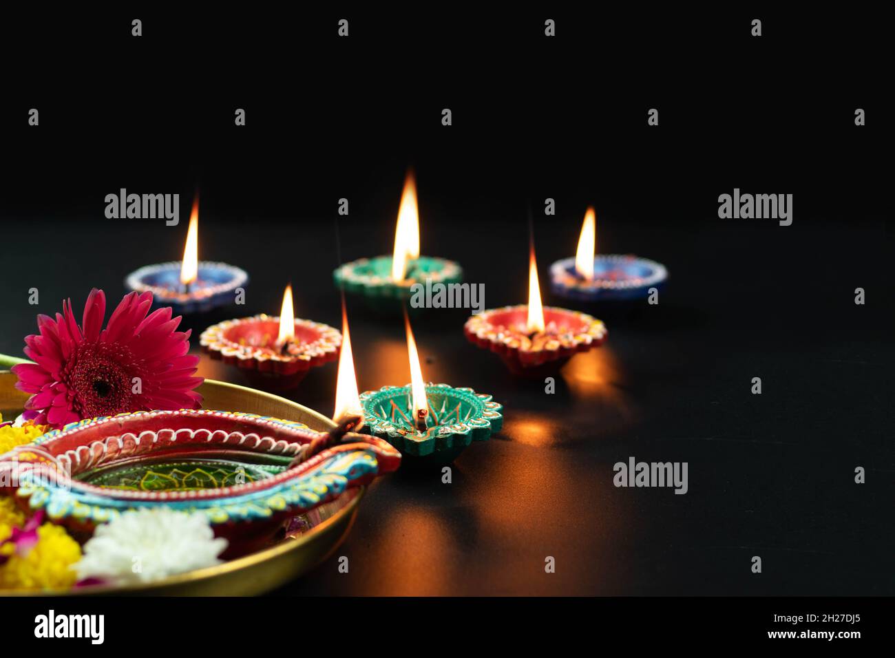 Diya d'argile fait à la main de différentes tailles, profond ou Dia illuminé en Thali sombre et doré décoré avec des fleurs de Phool.Thème pour Diwali Pooja, Navratri, Duss Banque D'Images