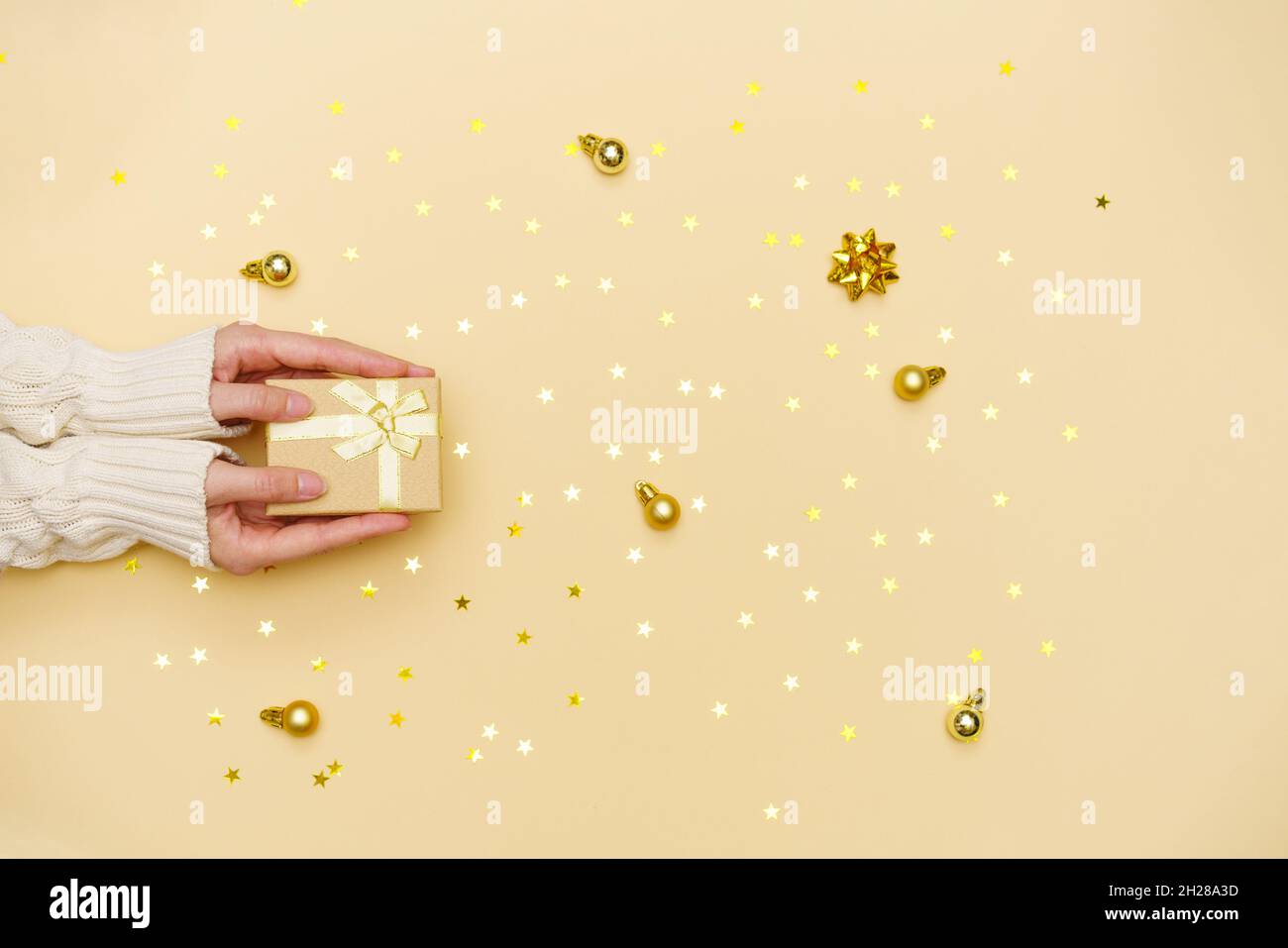 Les femmes tiennent la boîte cadeau joyeux noël sur fond jaune décoré de vacances, femme préparant la surprise, nouvel an hiver joyeux confetti dorés des étoiles, concept de vacances vrai, vue du dessus Banque D'Images