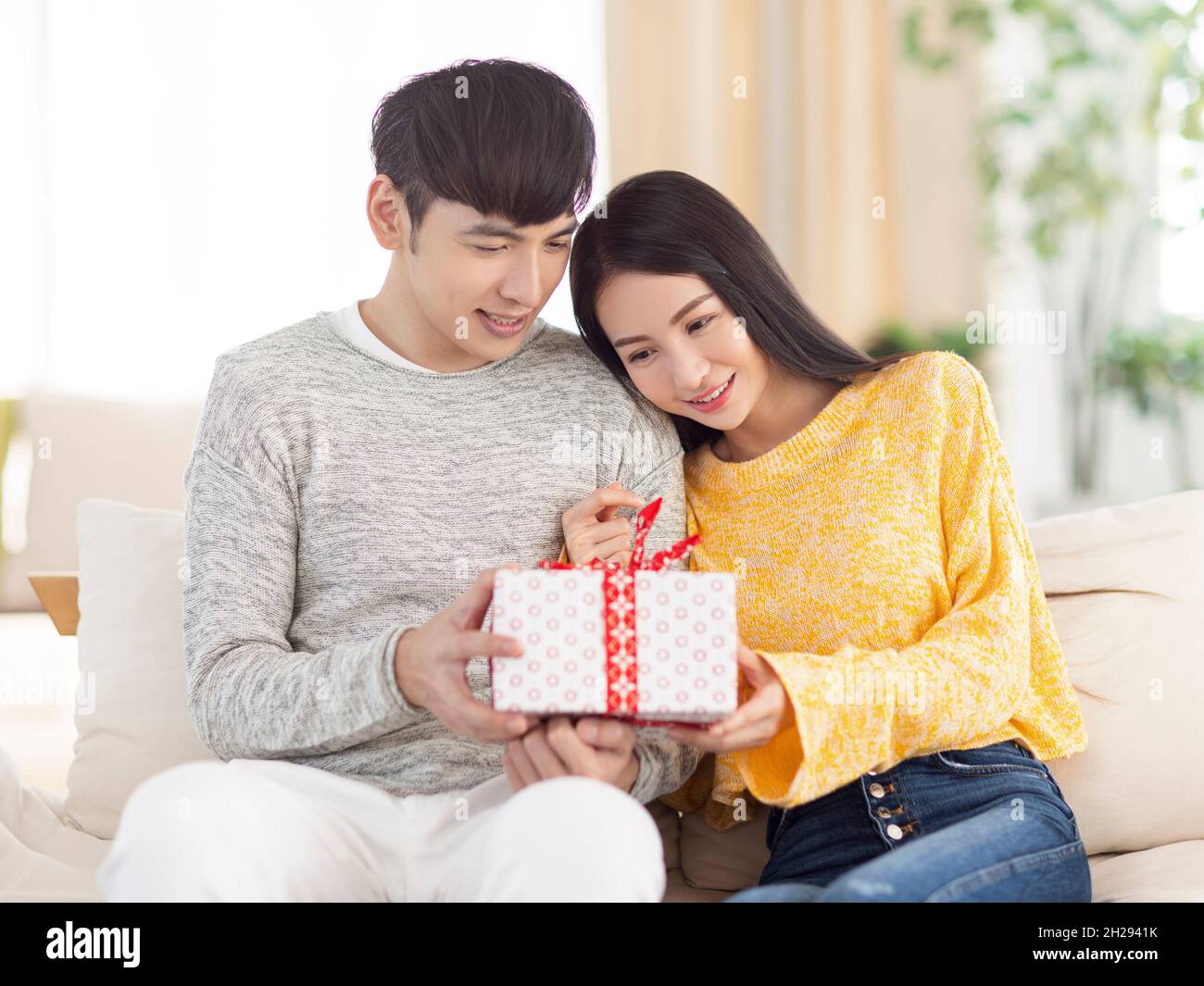 Un jeune couple partage un cadeau dans le salon Photo Stock - Alamy