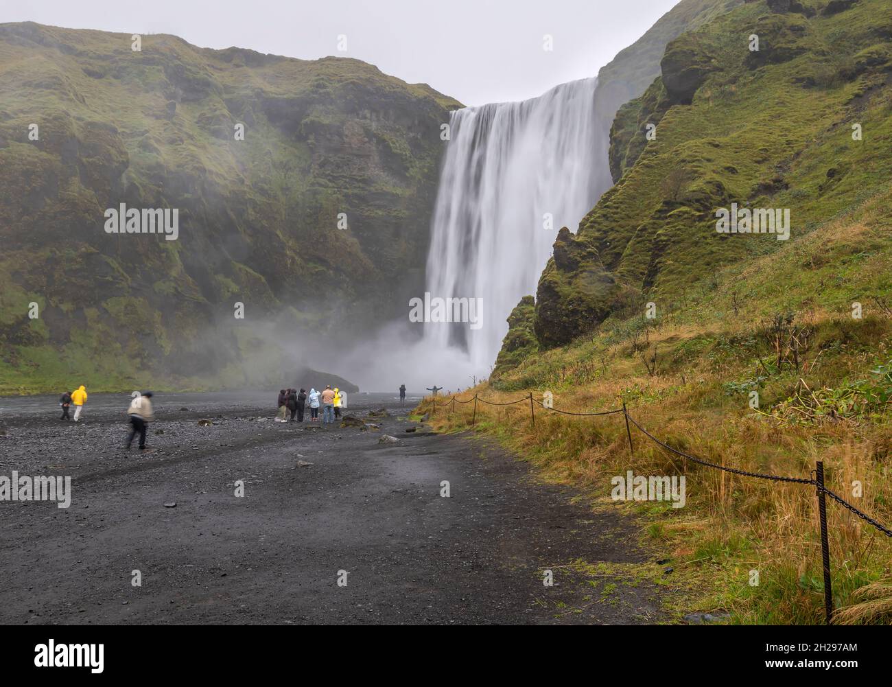 Les touristes voient et prennent des photos de Skógafoss un jour de pluie Banque D'Images