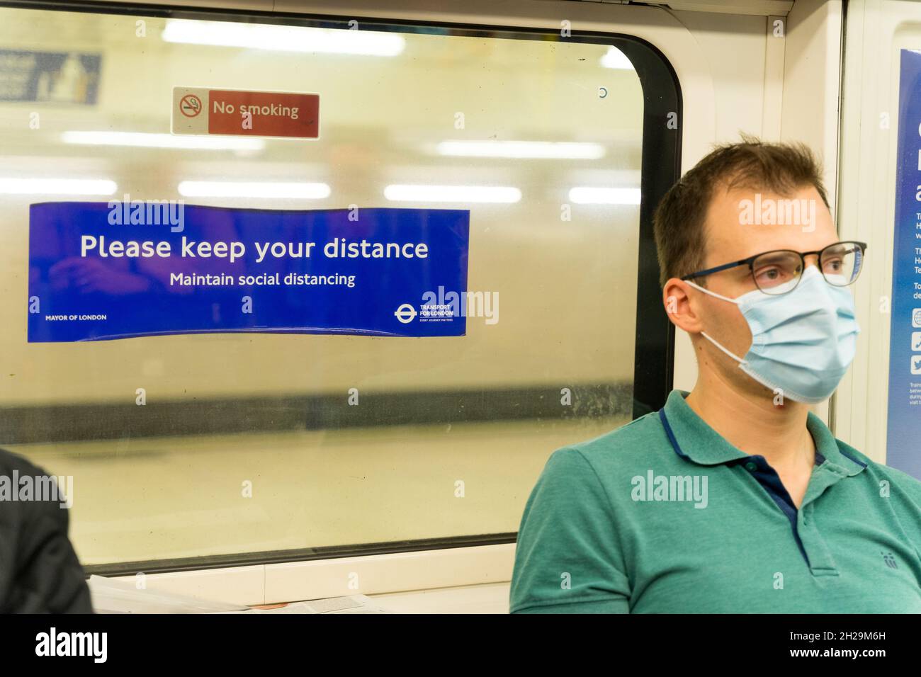 Le Male travelle de londres métro train se trouve à côté de la fenêtre où  un panneau d'affichage "Please Keep Your distance" Angleterre UK Photo  Stock - Alamy
