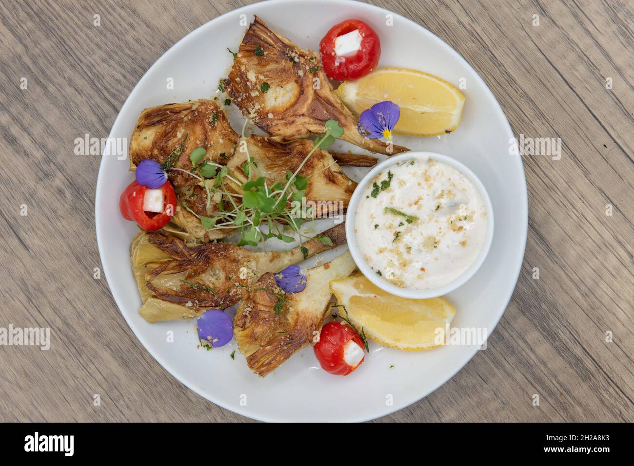 Vue en hauteur d'une assiette de coeurs d'artichaut disposés sur l'assiette et servis avec une sauce crémeuse. Banque D'Images