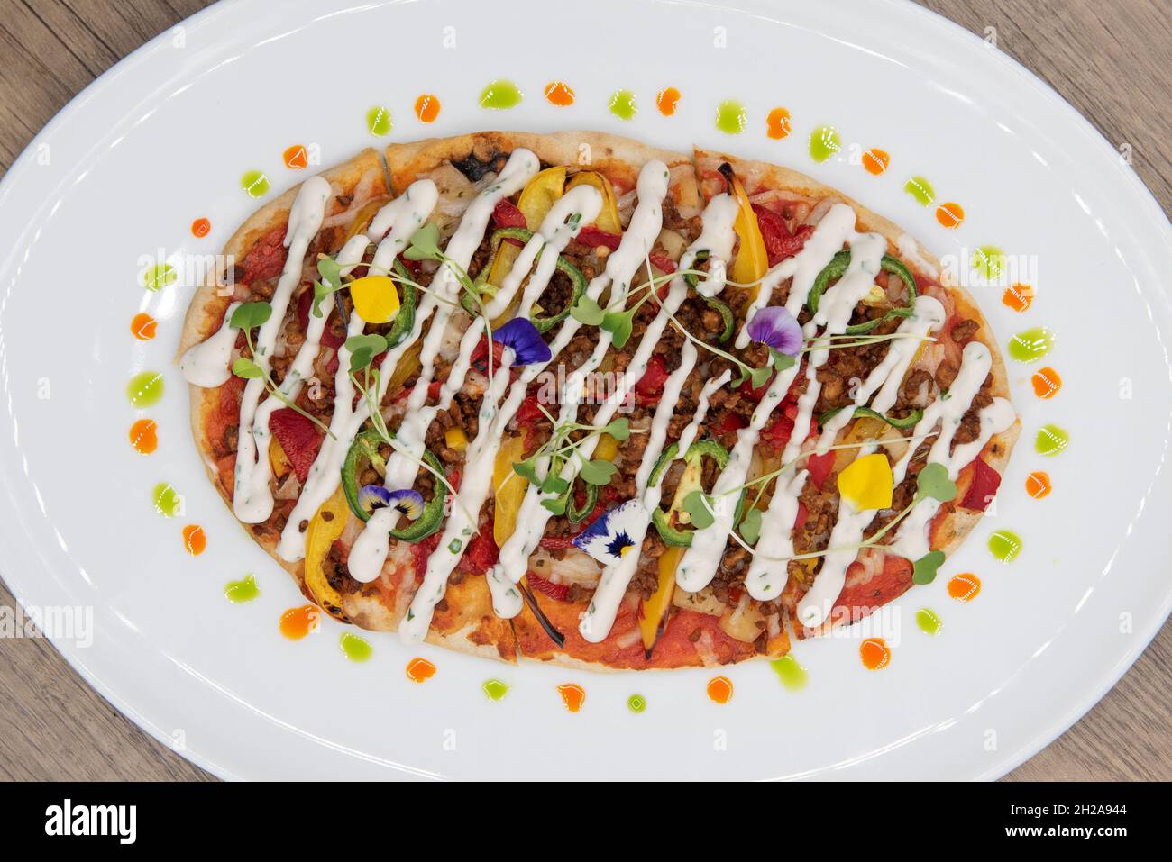 Vue en hauteur d'une pizza à pain plat ovale sur une assiette décorée avec des garnitures de légumes saines et une croûte mince. Banque D'Images