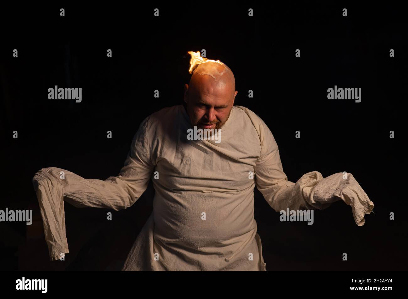 Homme chauve dans un blouson avec une tête brûlante sur un fond sombre. Banque D'Images