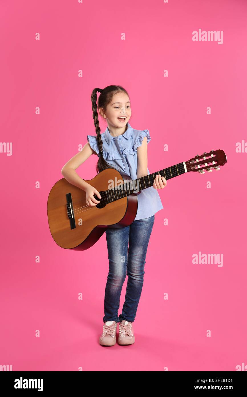 Jolie petite fille jouant de la guitare sur fond de couleur Photo Stock -  Alamy