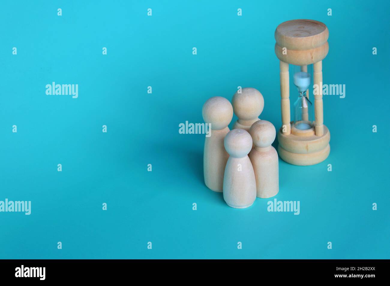 Un moment de qualité avec un concept de famille.Poupées en bois et sablier sur fond vert avec espace de copie Banque D'Images
