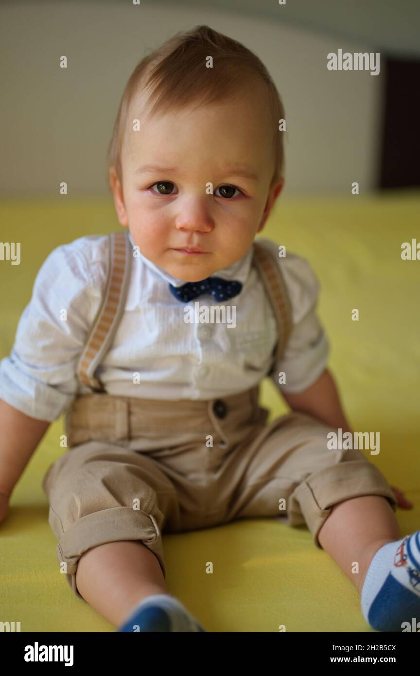 Joli Petit Bebe Assis Sur Le Lit Portant Une Chemise Avec Noeud Papillon Photo Stock Alamy