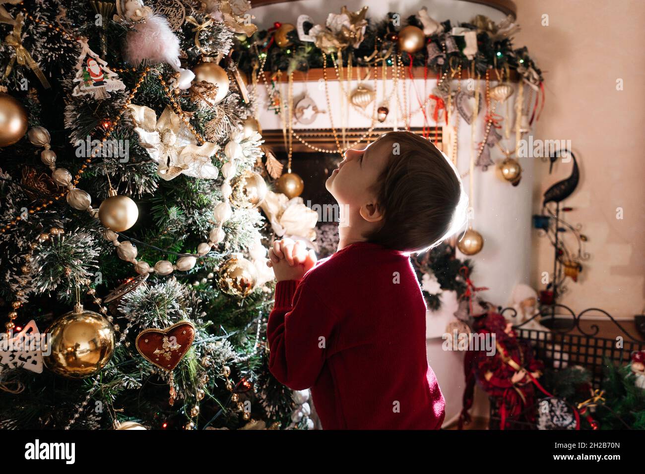 Support pour garçon près de l'arbre de noël, rétro-éclairage.Ambiance de fête en soirée.Concept nouvel an et noël. Banque D'Images