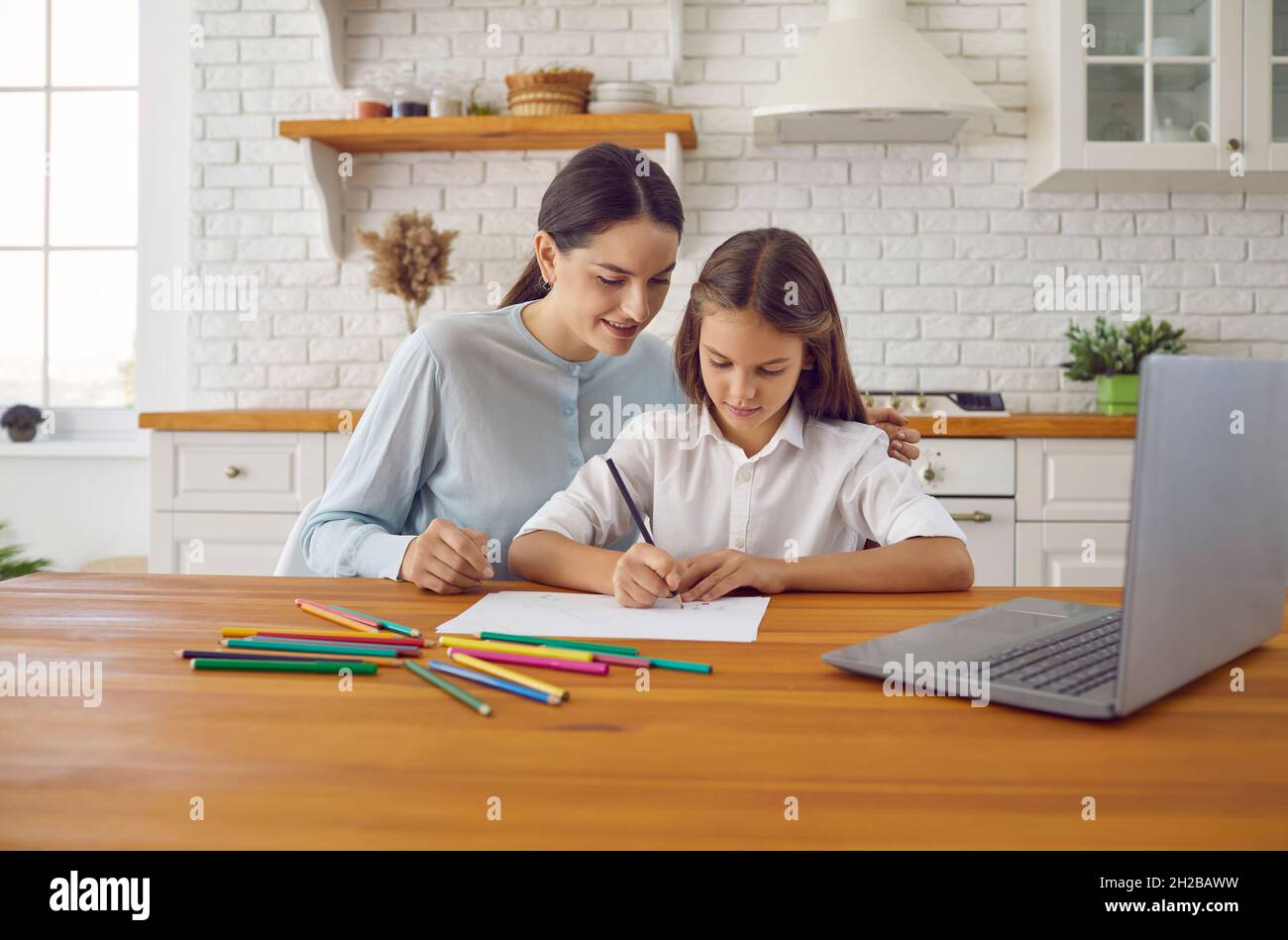 La mère et l'enfant regardant la leçon d'art sur ordinateur et de dessin d'image avec des crayons Banque D'Images