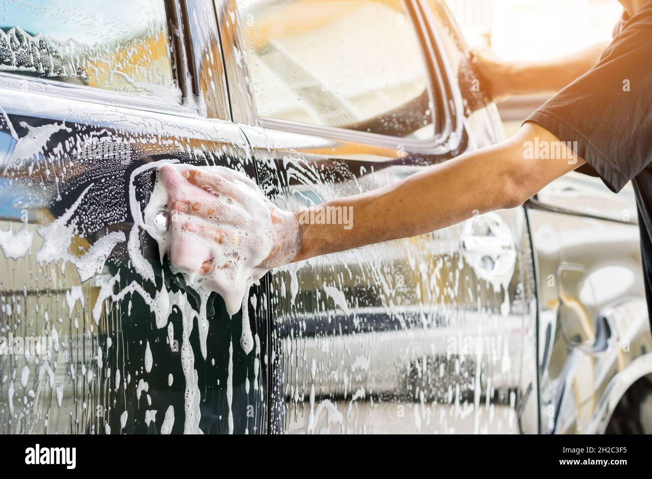 Le personnel du service automobile nettoie une voiture avec une éponge et un lave-auto détaillant et valeting concepts. Banque D'Images