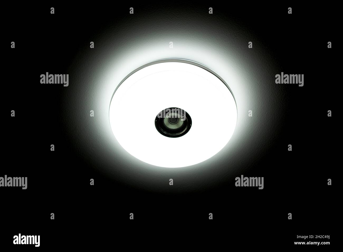 Plafonnier LED à lumière blanche avec haut-parleurs sans fil intégrés sur fond noir. Banque D'Images