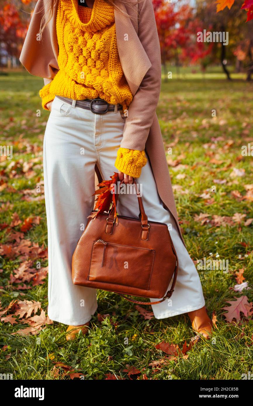 Femme à la mode portant des vêtements et des accessoires élégants marchant  dans le parc d'automne.Tenue automnale pour femme.Pantalon évasé tendance  avec chandail jaune, beige c Photo Stock - Alamy