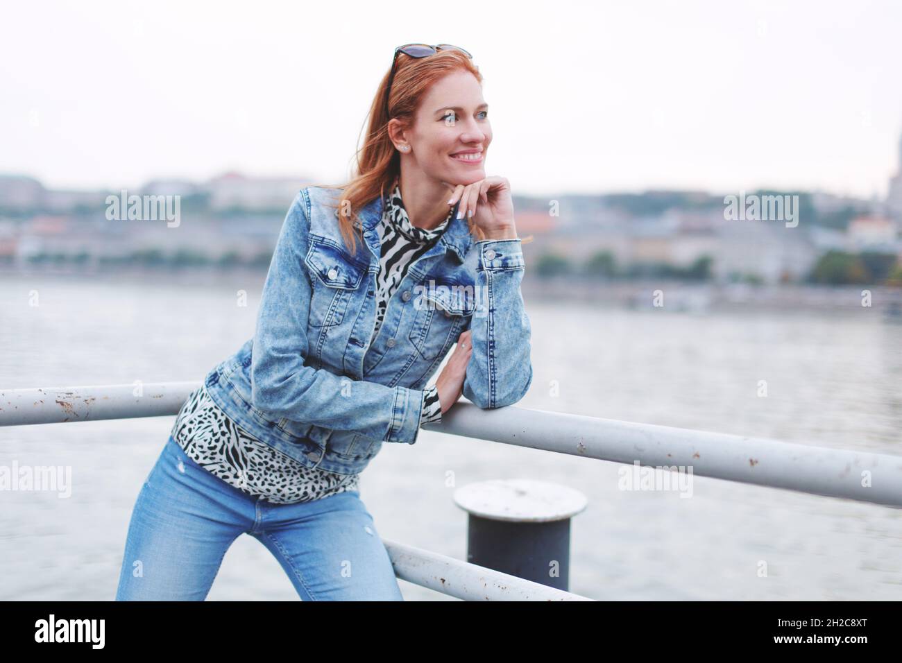 Femme à tête rouge positive regardant loin à la rive, foyer sélectif, Budapest, Hongrie Banque D'Images