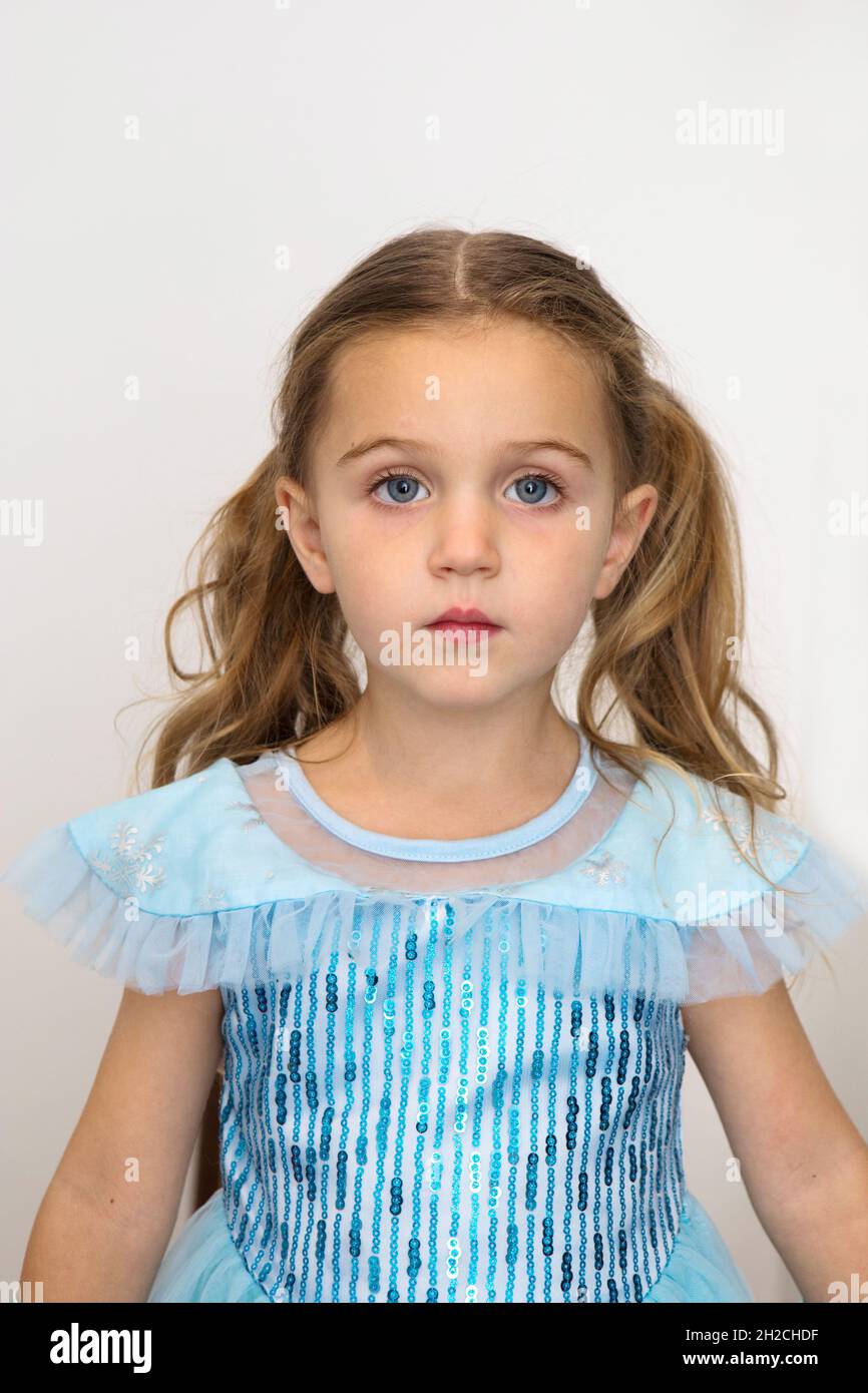 Adorable petite fille en robe princesse bleue regardant l'appareil photo sur fond blanc en studio 3 photo de trois ans pour passeport ou carte d'identité Banque D'Images