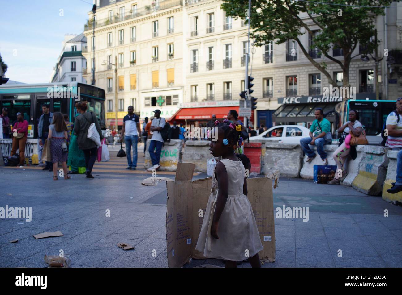 Enfant africain debout derrière une boîte de carton cassée, sur le trottoir dans le quartier mixte Afrique/Nord... - Château Rouge, Goutte d'Or, 75018 Paris, France Banque D'Images