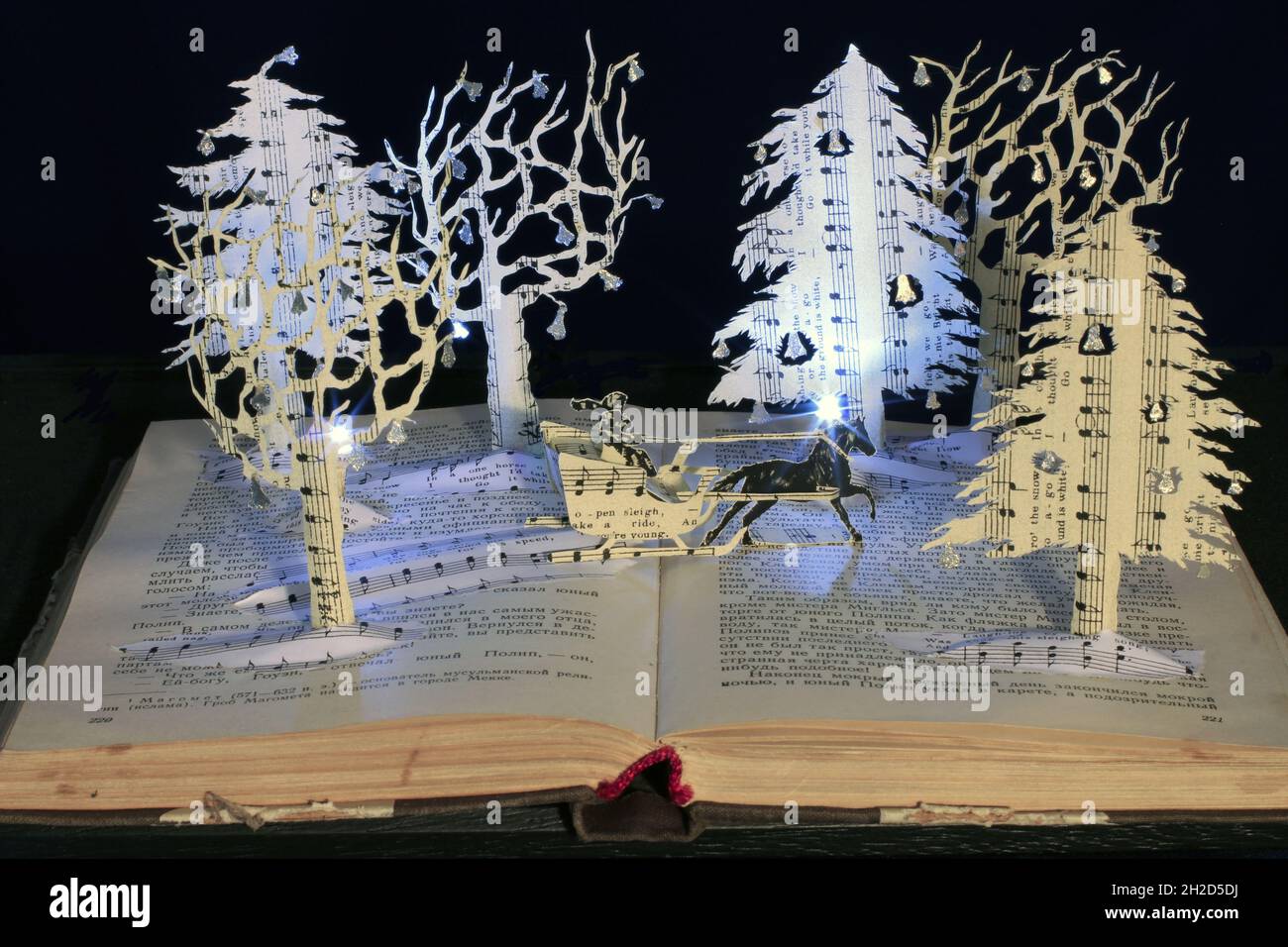 Interprétation papier faite à la main de Jingle Bells comme une scène de sculpture de livre.Un traîneau traverse un merveilleux pays hivernal magique. Banque D'Images