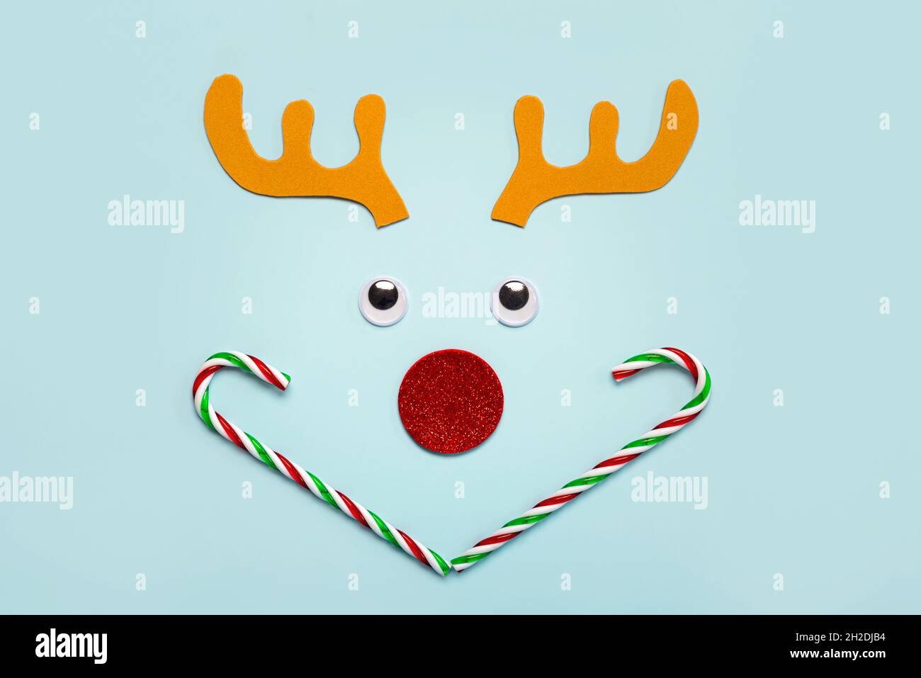 Joyeux Noël.Cornes de rennes de Noël Rudolph avec faux yeux et Cannes de bonbons rayées sur fond bleu.Arrière-plan du concept de Noël Banque D'Images