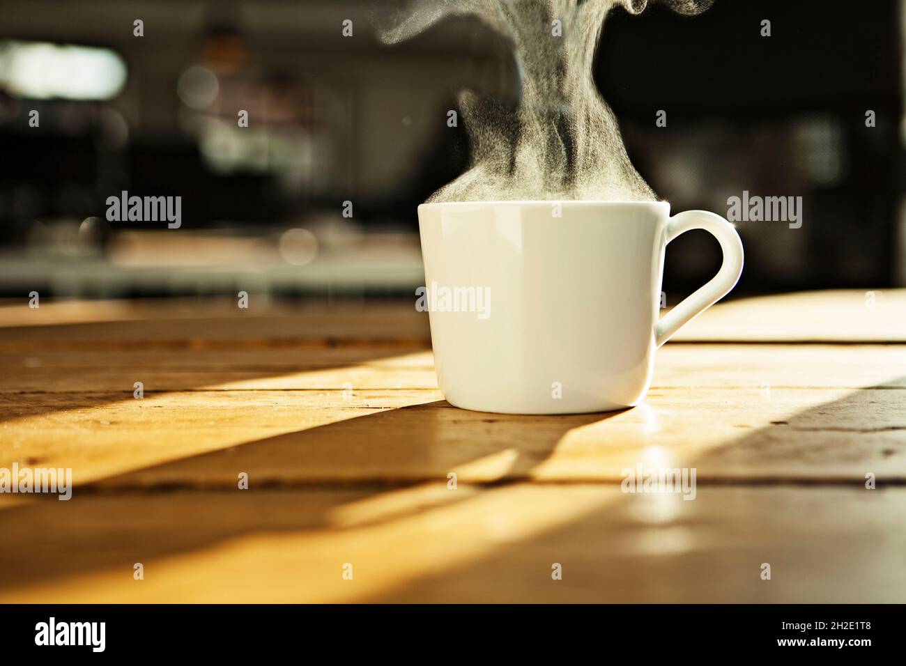 Tasse à café/thé blanc, tasse blanche avec boisson chaude sur table en bois, rétro-éclairée. Banque D'Images
