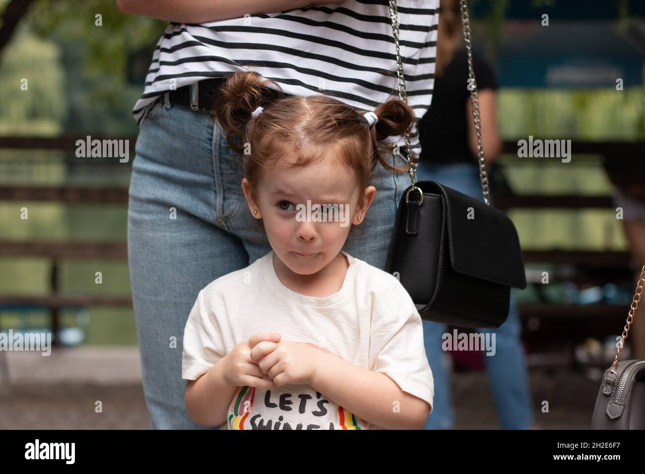 Une petite fille gaie avec des queues de cheval se tient devant sa mère dans la rue Banque D'Images