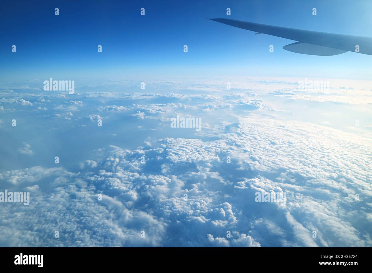 Aile d'avion sur un ciel bleu vif et des nuages blancs moelleux vue depuis la fenêtre de l'avion pendant le vol Banque D'Images