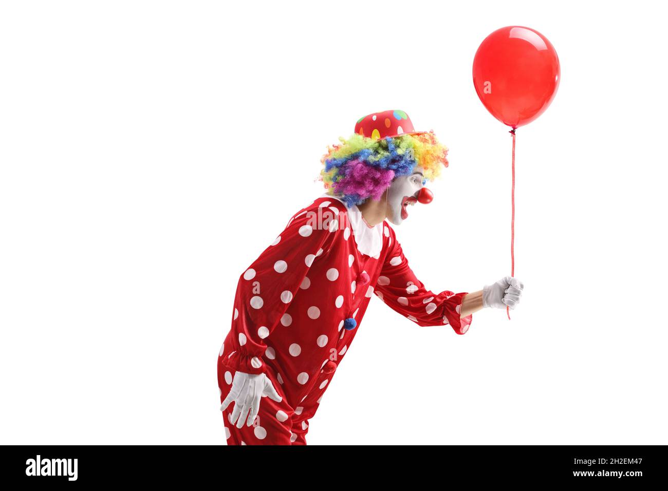 Plan de profil d'un clown donnant un ballon rouge isolé sur fond blanc Banque D'Images