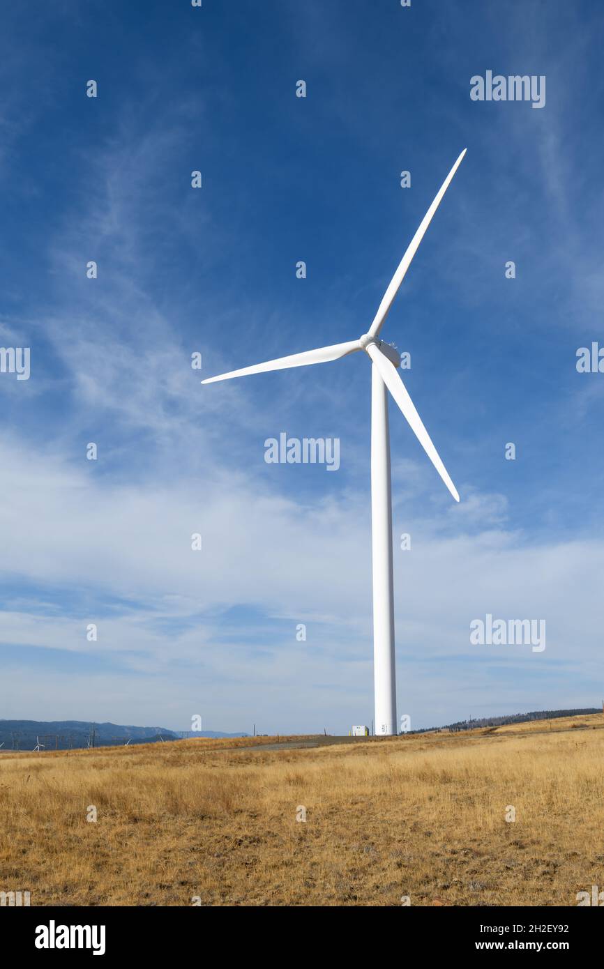 Une éolienne dans le comté de Kittitas, Washington, se dresse sur une colline aride sous un ciel bleu avec de hauts nuages car elle génère une énergie alternative propre Banque D'Images