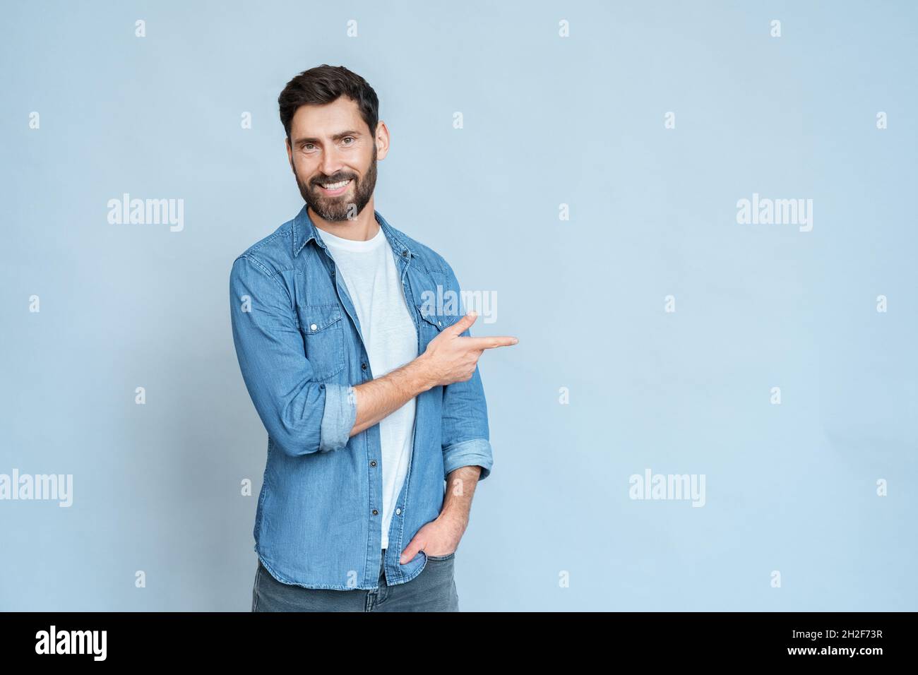 Homme souriant indépendant pointant vers la droite avec l'index et regardant la caméra Banque D'Images