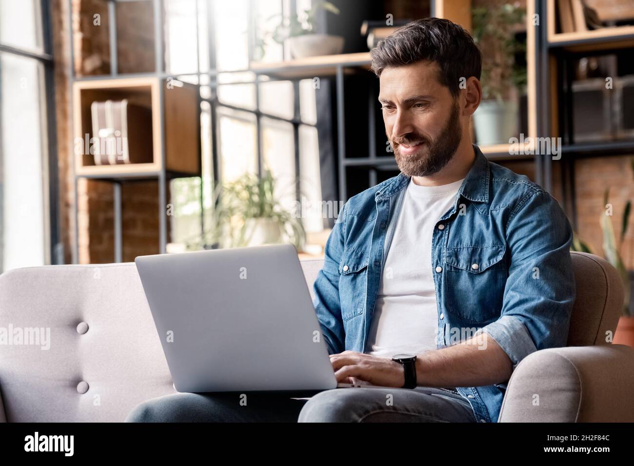 Jeune homme adulte concentré utilisant un ordinateur portable, en tapant sur le clavier, en écrivant un message Banque D'Images