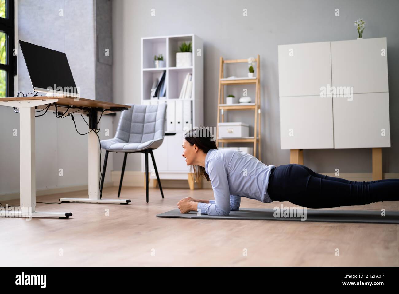 Une femme effectuant un entraînement d'exercice de planche de bureau Banque D'Images