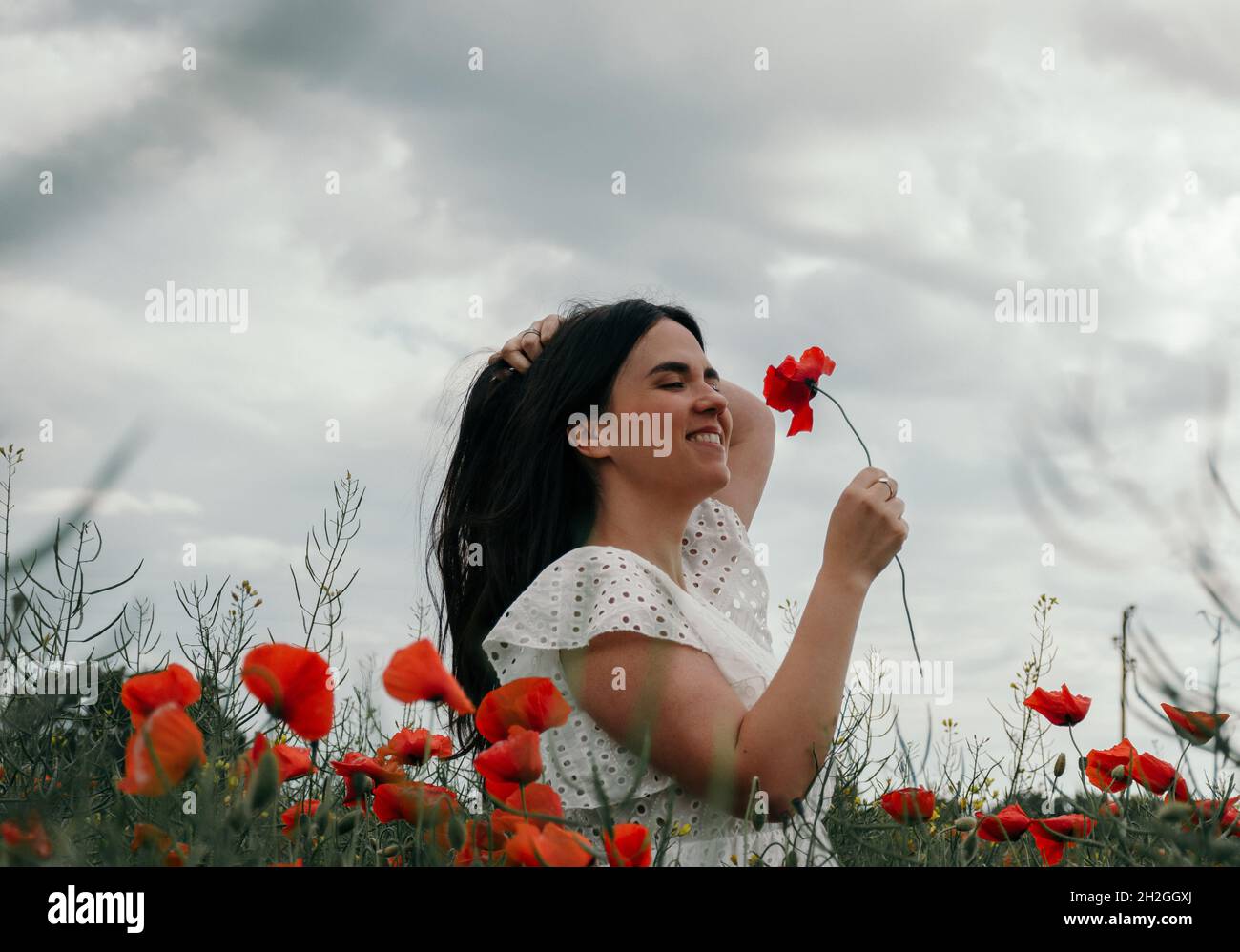 Belle jeune femme vêtue de robe blanche, debout dans le champ de pavot Banque D'Images