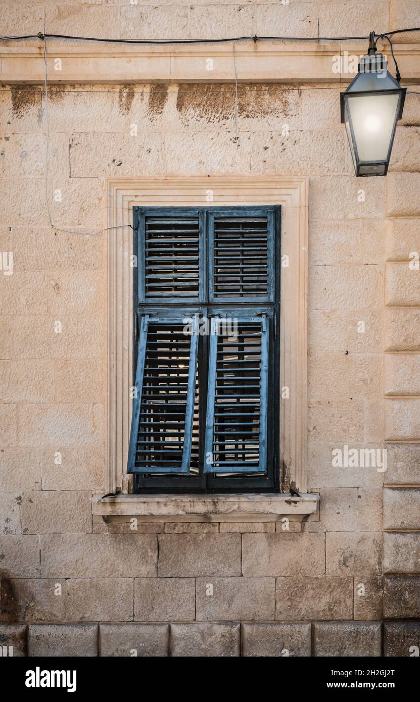 Vieille fenêtre avec volets peints en bleu entrouvert. Banque D'Images