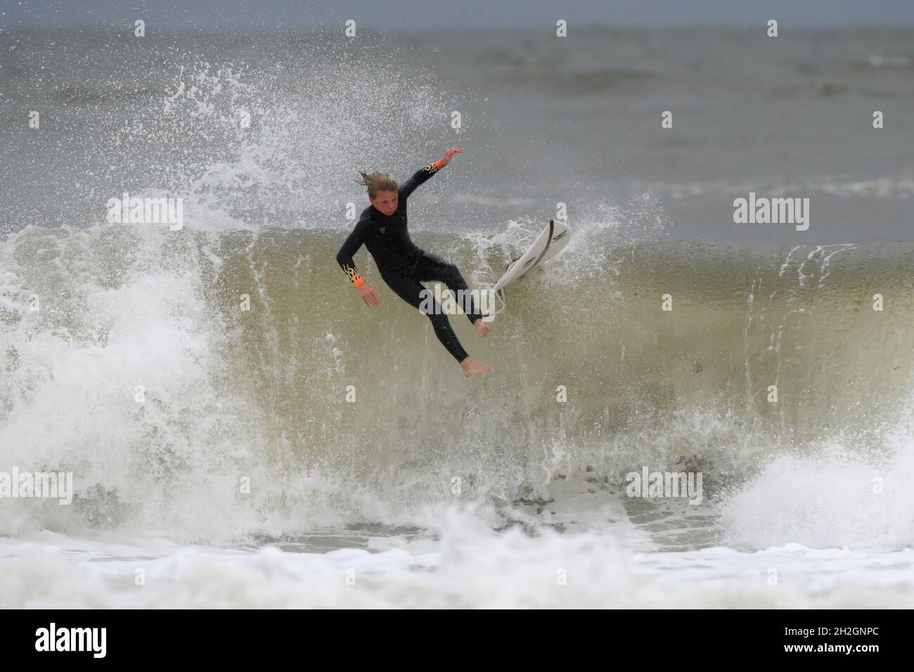 Eessuyer - un jeune surfeur passe « au-dessus des chutes » de la vague avec une planche (fixée par la laisse) en suivant de près derrière. Banque D'Images