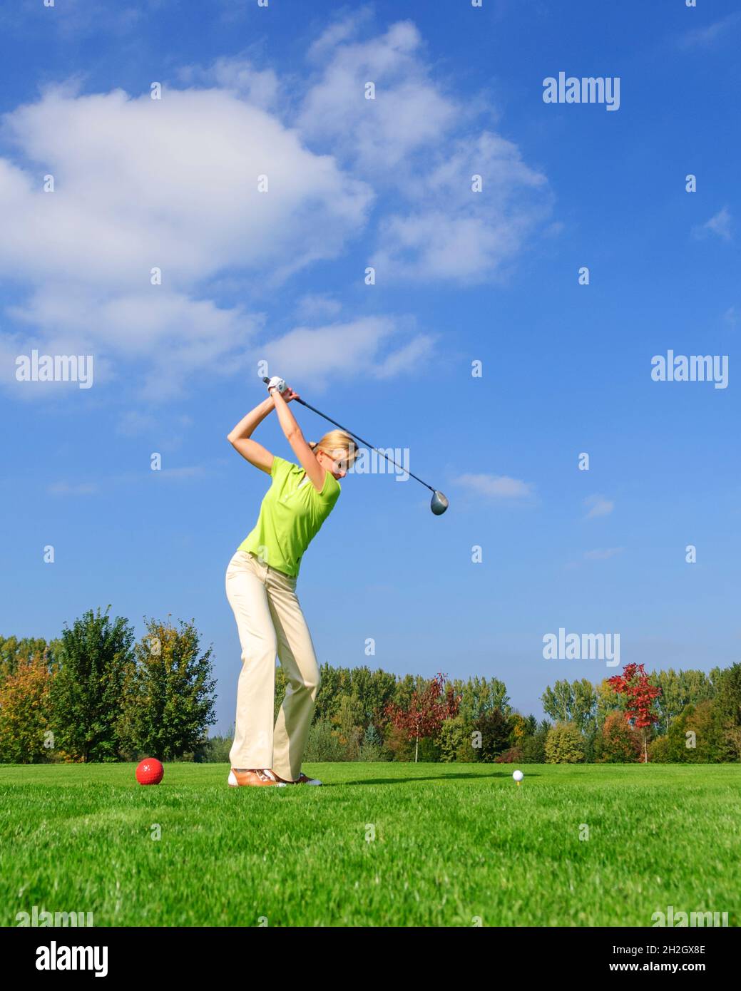 Une joueuse de golf attirante frappe le ballon du tee Banque D'Images