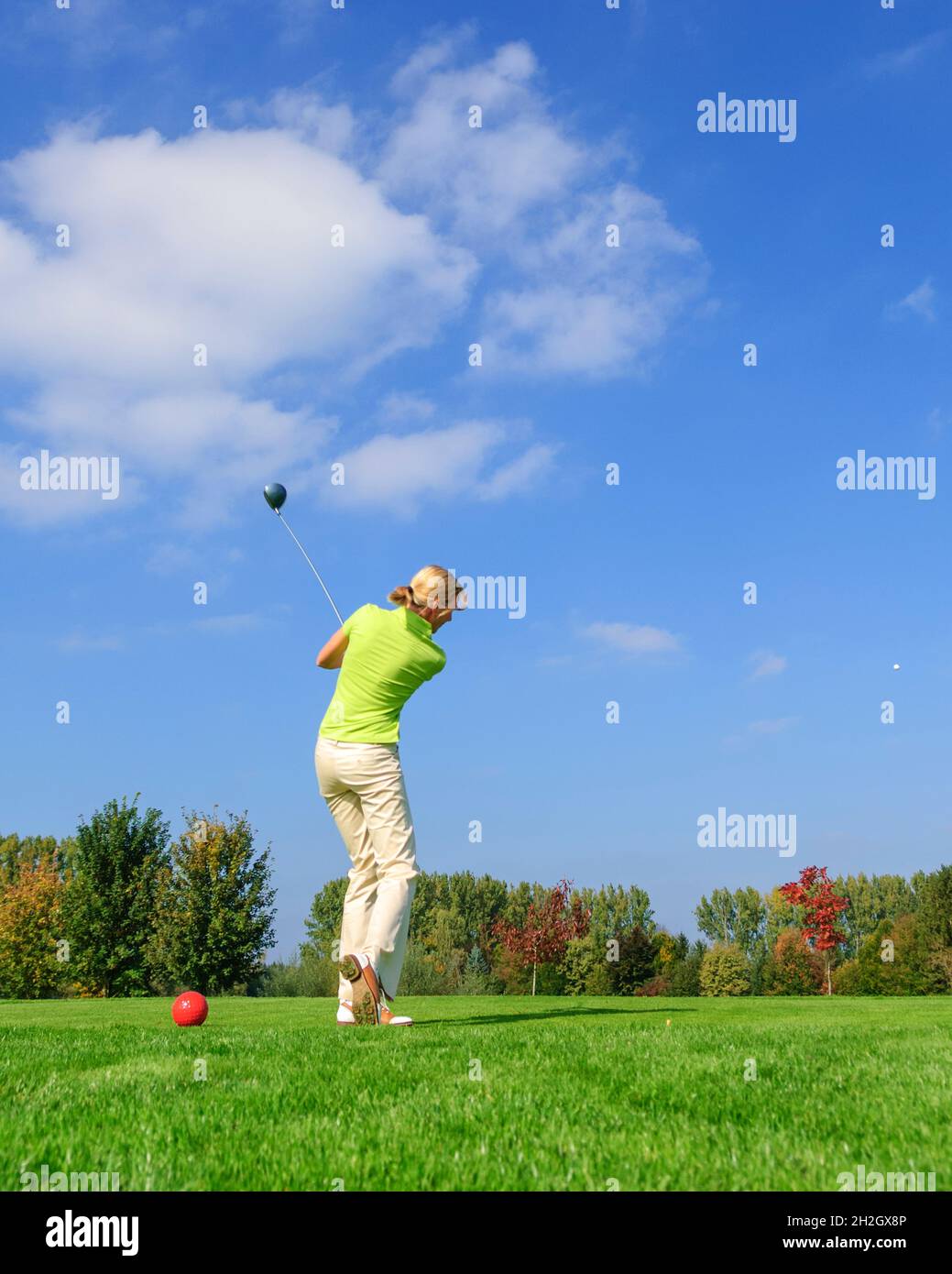 Une joueuse de golf attirante frappe le ballon du tee Banque D'Images