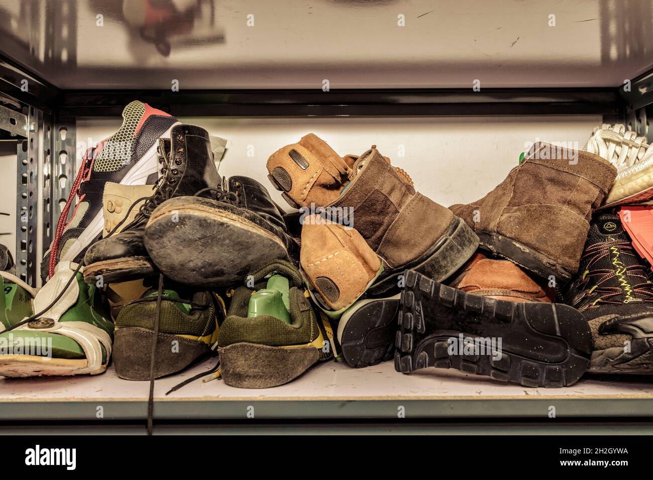 Chaussures dans un atelier de réparation, empilées et désordonnées. Banque D'Images