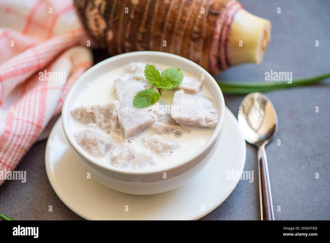 Taro alimentaire avec dessert taro bouilli avec du sucre et du lait de coco sur un bol et de la racine de taro frais cru bio prêt à cuire, cuisine thaïlandaise asiatique Banque D'Images