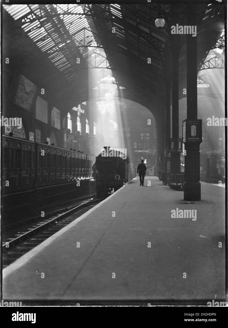 Liverpool Street Station, Liverpool Street, City of London, Greater London Authority, c1932.En regardant le long d'une plate-forme à Liverpool Street Station vers un personnage passant devant une machine à vapeur, avec un faisceau de lumière du soleil qui brille à travers le toit du hangar. Banque D'Images