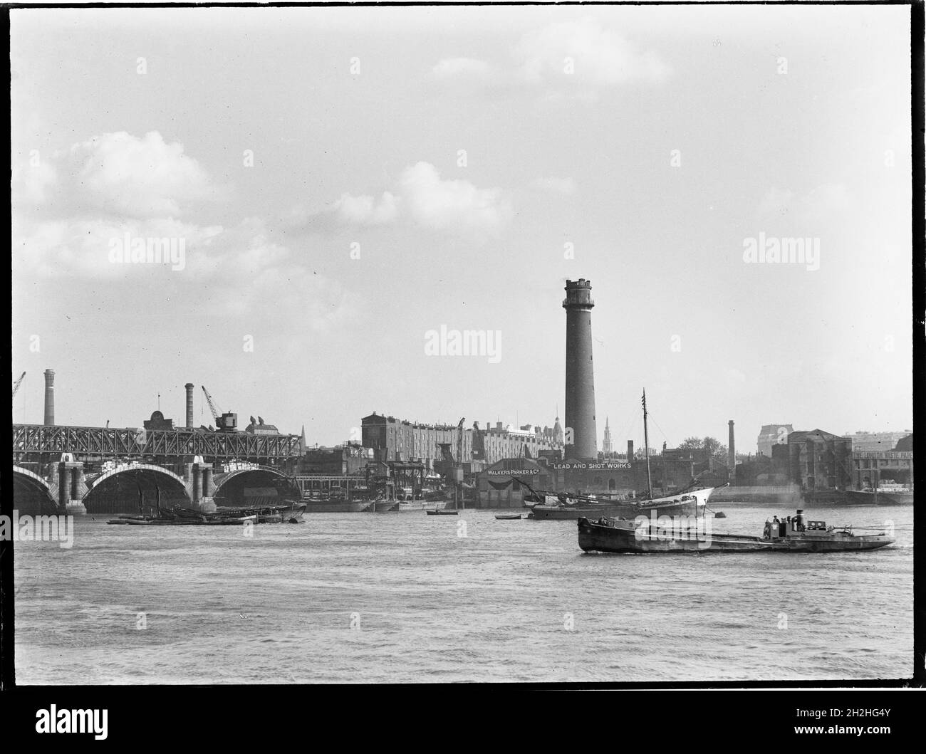 Tour de tir et Lead Works, Belvedere Road, Lambeth, Greater London Authority, 1936.Vue sur la Tamise vers la tour de tir de Lambeth Lead Works, montrant la démolition de l'ancien pont de Waterloo sur la gauche et un bateau naviguant vers le pont.La tour de tir du Lambeth Lead Works a été conçue par David Ridall Roper et a été construite en 1826 pour Thomas Maltby & Co. Au moment de cette photographie, elle était exploitée par Walkers, Parker & amp;Co mais il a été démoli plus tard en 1962 pour faire place à la salle de la Reine Elizabeth.Le pont de Waterloo, qui est présenté pendant sa demi-oli Banque D'Images